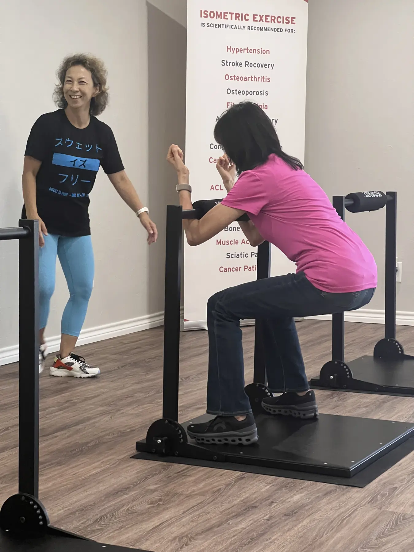 An adult member receiving individualized coaching during an isometric training session at Sweat Is Free